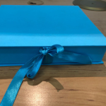 Bright blue hinged lid box with a matching blue ribbon closure.