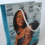 High-gloss paper bag with full-color photographic branding and white braided cord handles.