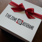 White rigid gift box featuring black branding and a deep red satin ribbon bow.