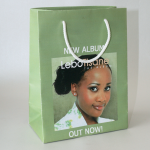 Sage green matte-finish paper bag featuring a portrait printing and white rope handles.