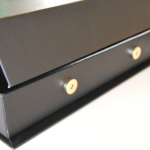 Close-up of an exposed circular metallic magnet embedded in a rigid box edge.