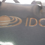 Close-up of a black high-gloss paper bag featuring copper-toned metallic foil stamping.