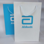 Blue and white matte-finish paper bags with matching white cord handles and blue branding.