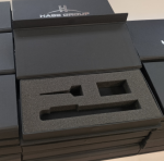 Open black hinged lid box featuring a high-density charcoal foam insert with three custom die-cut cavities.