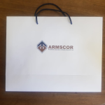 Large white landscape paper bag with minimalist branding and blue cord handles.