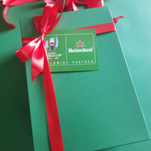 Large green rigid box with a red ribbon and a printed sponsorship tag.