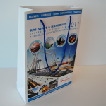 White matte-finish paper bag featuring high-definition photographic event branding and blue cord handles.