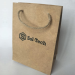 Medium-format natural kraft paper bag featuring a black silkscreened logo and jute cord handles.