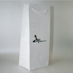 Tall, narrow-format white paper bag featuring a center-aligned silver foil logo and white cord handles.