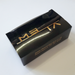 High-gloss black tuck-in lid box with precision gold foil typography.