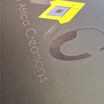 Close-up of yellow and blue graphics with DTF branding on a textured black substrate.