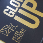 Metallig gold silk-screened branding on a heavily textured black paper substrate.