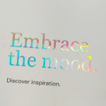 Spectrum-shifting holographic foil typography on a matte white substrate.